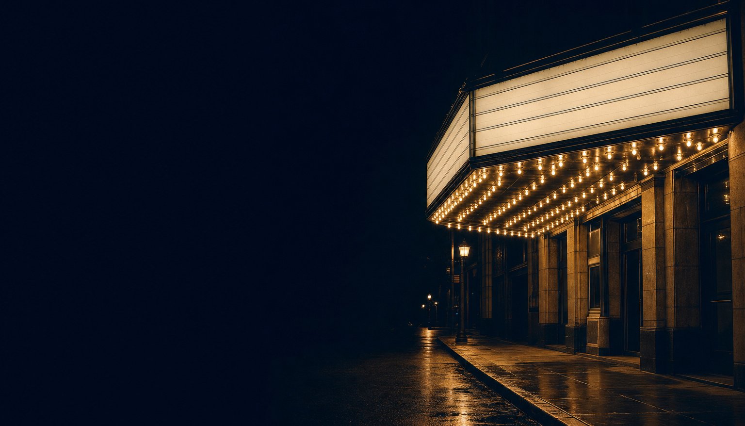 The underside of an old cinema marquee at night, its rows of filament bulbs lit and its letter board empty.